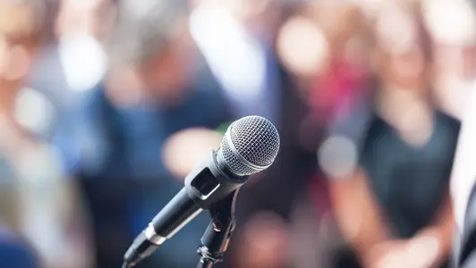 Microphone in focus against blurred audience Mikrofon