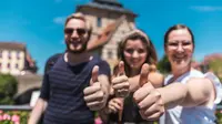 Sommer in Bamberg Studierende stehen draußen und zeigen den Daumen nach oben. Im Hintergrund ist das alte Rathaus zu sehen