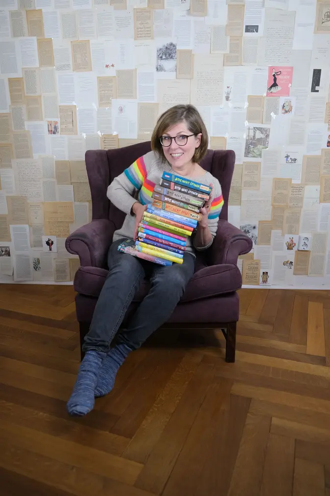 Charlotte Habersack in einem Sessel mit einem Stapel Bücher auf dem Schoß.
