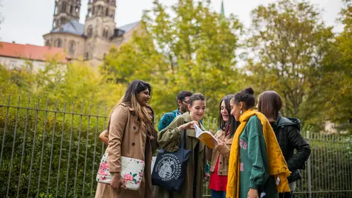 Students in Bamberg Studierende schauen draußen gemeinsam ins Buch