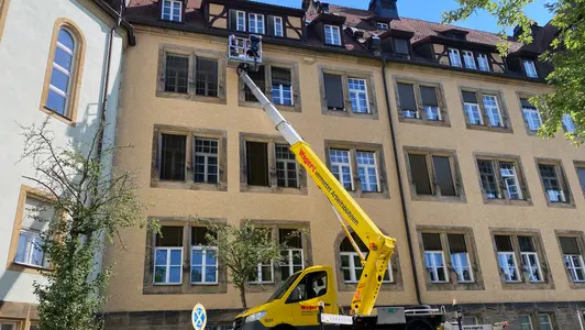 Nistkästen für Mauersegler werden mit Hilfe eines Krans an der Fassade befestigt.