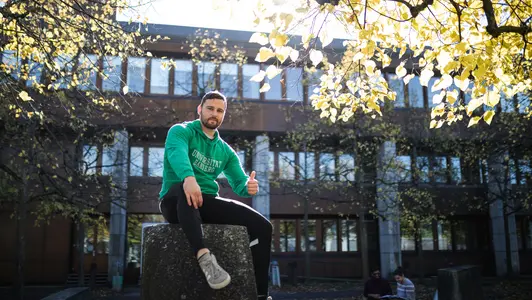 Person sitzt im Herbst vor der Bibliothek in der Feldkirchenstraße.