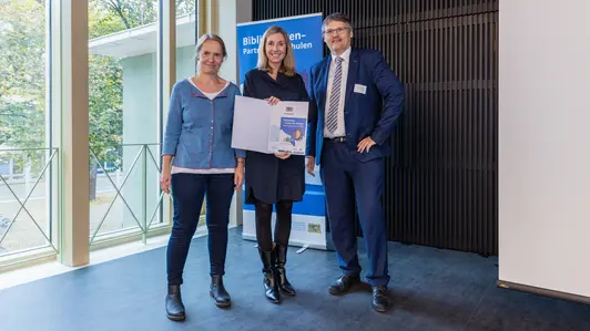 Kultusministerin Anna Stolz (Mitte) überreichte Christiane Lauterbach und Fabian Franke von der Bamberger Universitätsbibliothek das Gütesiegel „Bibliotheken – Partner der Schulen“.